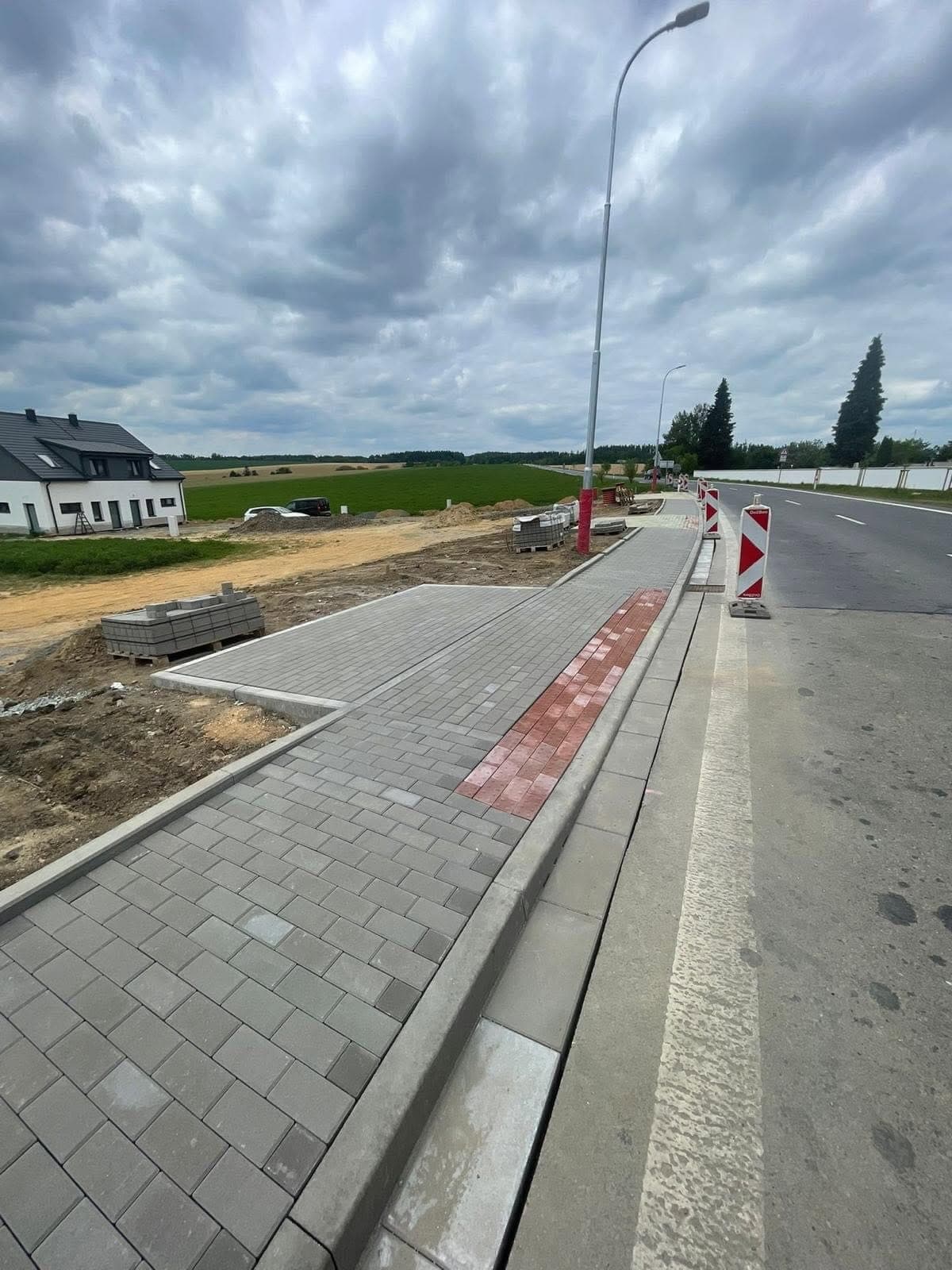 Chodník v Domašově — Výstavba nového chodníku podél komunikace — výkop, podkladní vrstvy, obruby a dlážděný pov